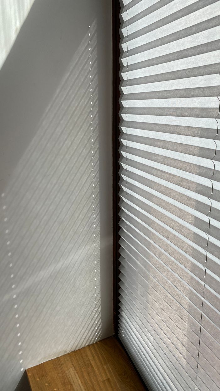 gallery-02 Sunlight creates captivating shadows on a wall through a modern roller blind.
