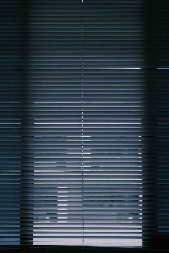 gallery-01 A vertical interior shot of closed window blinds creating a moody atmosphere.