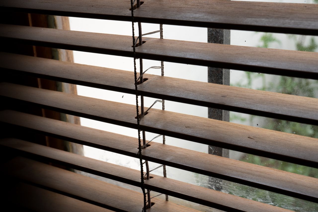 Wooden window blinds casting shadows indoors in Argentina. Perfect for cozy home interior themes.