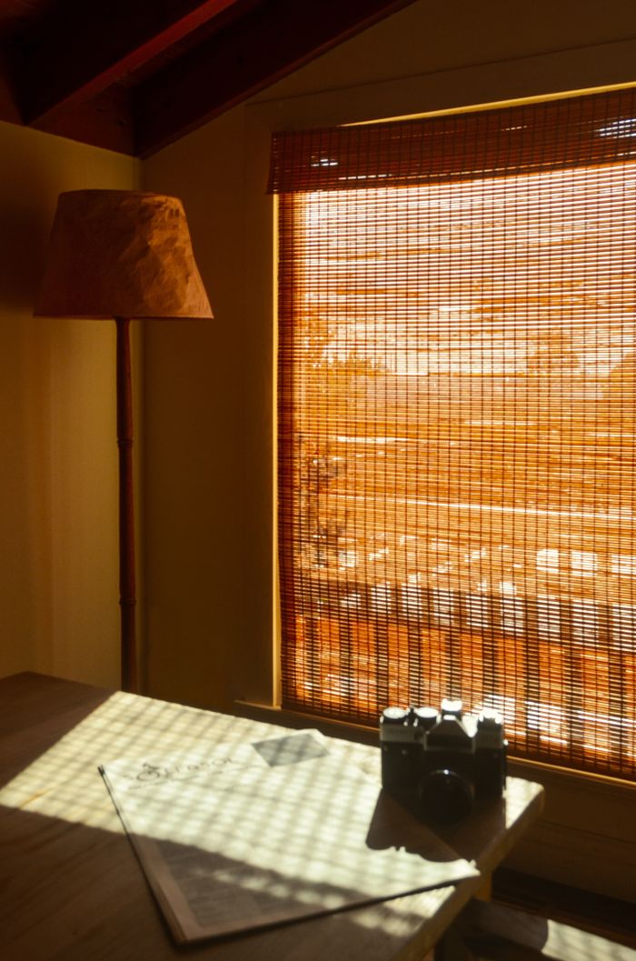 services-01 Vintage photo camera on newspaper on desk against lamp and straw curtain at home in sunlight